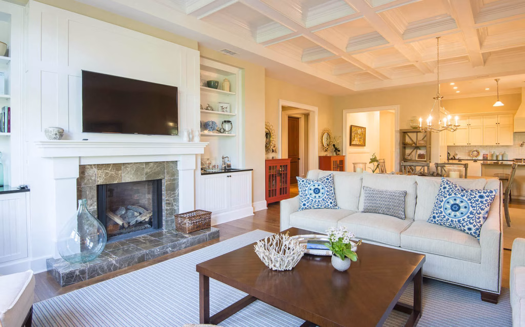 Exquisite interiors include walnut flooring, handsome trims and moldings, wainscoting and beadboard accents, shiplap detailing, tray and coffered ceilings, solid wood doors, and a soothing color palette with professional decorator furnishings and touches. The living room features a marble-surround fireplace with custom hearth, handcrafted built-ins, wet bar, and oversized sliding glass doors out to the covered porch.